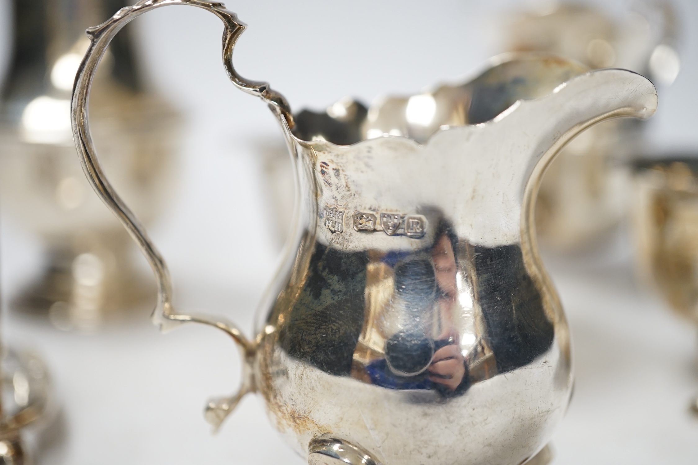 Two 20th century silver cream jugs, two silver sugar bowls, a silver toastrack and a silver caster, 18.5oz.